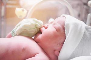 Newborn baby inside incubator in hospital post delivery room photo