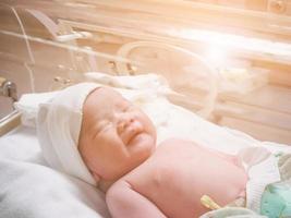 Newborn baby inside incubator in hospital post delivery room photo