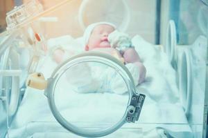 Newborn baby inside incubator in hospital post delivery room photo