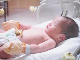 Newborn baby girl inside incubator in hospital post delivery room photo