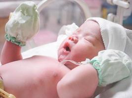 Newborn baby girl inside incubator in hospital post delivery room photo