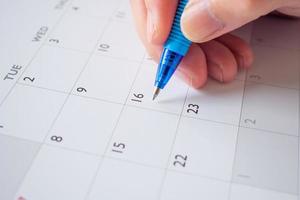 Woman hand with pen writing on calendar date business planning appointment meeting concept photo