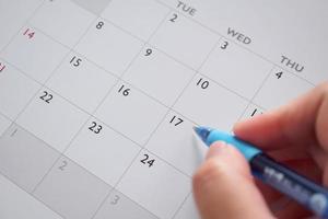 mano de mujer con bolígrafo escribiendo en la fecha del calendario concepto de reunión de cita de planificación empresarial foto