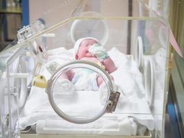 Newborn baby inside incubator in hospital post delivery room photo