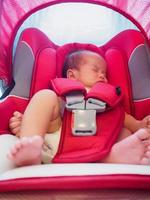 el bebé recién nacido se sienta en el asiento del automóvil por seguridad foto