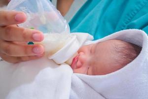 Mother feeding newborn baby from the bottle photo