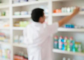 blur pharmacist taking medicine from shelf in the pharmacy photo