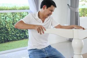 hombre asiático montando muebles de mesa blanca en casa foto