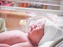 Newborn baby inside incubator in hospital post delivery room photo