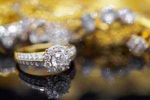 anillos de diamantes de joyería de oro de lujo con reflejo en el fondo negro foto