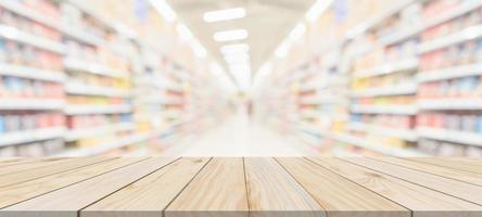 mesa de madera con fondo borroso interior del pasillo de la tienda de comestibles del supermercado con luz bokeh para la exhibición del producto foto