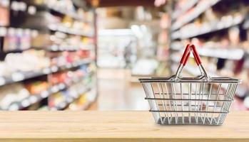 cesta de la compra vacía en la mesa de madera sobre el fondo borroso del supermercado de la tienda de comestibles foto