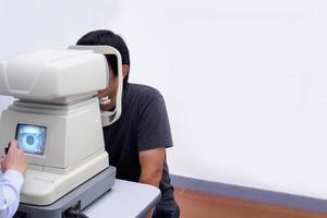 Young handsome asian man take eye exam with optical eye test machine photo