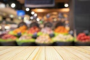 Empty wood table top with abstract blur colorful Fruits in display basket in supermarket grocery store defocused background with bokeh light photo