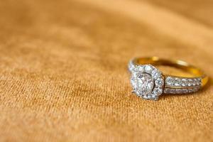 Jewelry diamond ring on golden fabric background close up photo