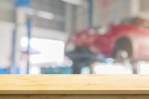 Empty wood table top with car service centre auto repair workshop blurred background photo