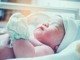 Newborn baby girl inside incubator in hospital post delivery room photo