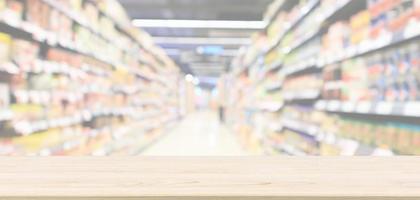 Empty wood table top with abstract supermarket aisle interior blurred defocused background with bokeh light photo