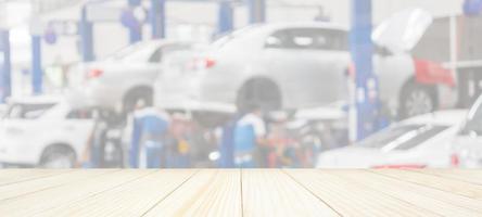 Empty wood table top with car service centre auto repair workshop blurred background photo