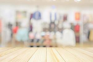 Empty wood table top with modern clothing store interior blur abstract defocused background with bokeh light for product display photo