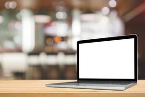 Blank white screen laptop computer on wood table top with cafe restaurant abstract bokeh light defocused blur background photo