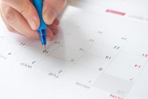 mano de mujer con bolígrafo escribiendo en la fecha del calendario concepto de reunión de cita de planificación empresarial foto