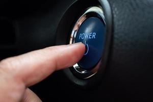 Hand push on car engine power start button close up photo