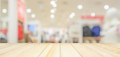 Empty wood table top with modern clothing store interior blur abstract defocused background with bokeh light for product display photo