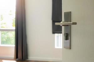 Modern door handle on white door with room interior photo