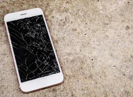 broken glass of mobile phone screen on concrete floor background photo