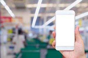 Woman hand holding mobile phone at supermarket checkout background photo