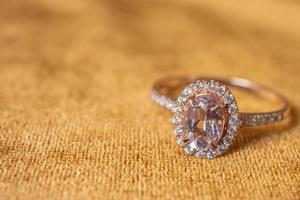 Jewelry pink diamond ring on golden fabric background close up photo