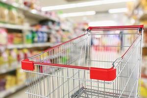 Empty shopping cart with abstract blur supermarket discount store aisle and product shelves interior defocused background photo