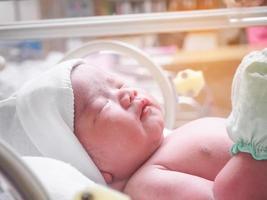 Newborn baby inside incubator in hospital post delivery room photo