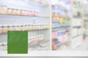 Paper bag on Pharmacy drugstore counter table with medicine and healthcare product on shelves blur background photo