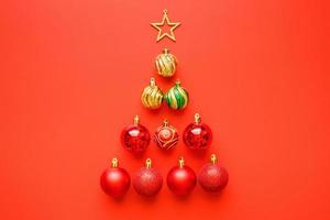árbol de navidad de bolas y estrella dorada sobre fondo rojo foto