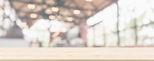 Empty wooden table top with cafe restaurant or coffee shop window interior abstract blur defocused with bokeh light background for montage product display photo