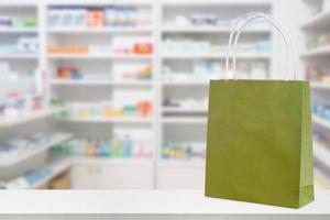 bolsa de papel en la mesa del mostrador de la farmacia con medicamentos y productos sanitarios en los estantes fondo borroso foto
