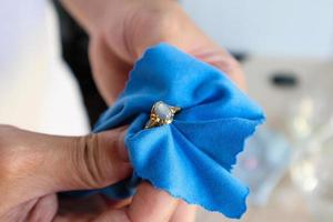 Jeweller hand polishing and cleaning gold jewelry ring with micro fiber fabric photo