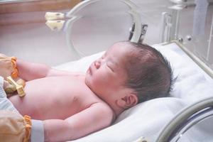 Newborn baby girl inside incubator in hospital post delivery room photo