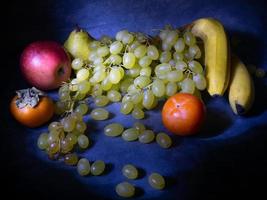 Still life of fruits. apple, persimmon, pear and grapes on a black background. Persimmon Chamomile. Apple Gala. Pear Lucas. Healthy eating. Vegetarianism photo