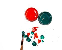 Jars of green and red acrylic paint on a white background and splattered paint on the table. photo