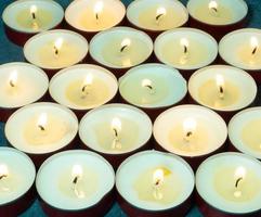 Lots of small lit candles.  Candle background.Flat round candles in red metal stands photo