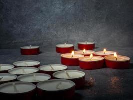 Short candles are burning against a dark background. Lots of small candles. Not all candles are lit. photo