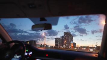 vista desde la ventana delantera de un coche que circula por una concurrida carretera iluminada por farolillos por la noche. concepto de vehículo y transporte. video