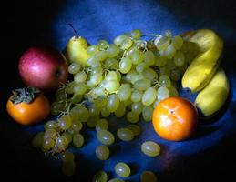 Still life of fruits. apple, persimmon, pear and grapes on a black background.  Persimmon Chamomile. Apple Gala. Pear Lucas. Healthy eating. photo