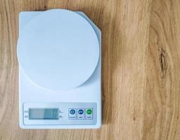 Digital white kitchen scales on wooden table.