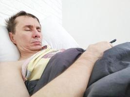 hombre durmiendo en la cama con el teléfono en las manos foto