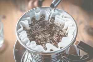 Barista pouring hot water on ground coffee with filter to make a dip coffee. photo