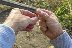 Fisherman tying a hook photo